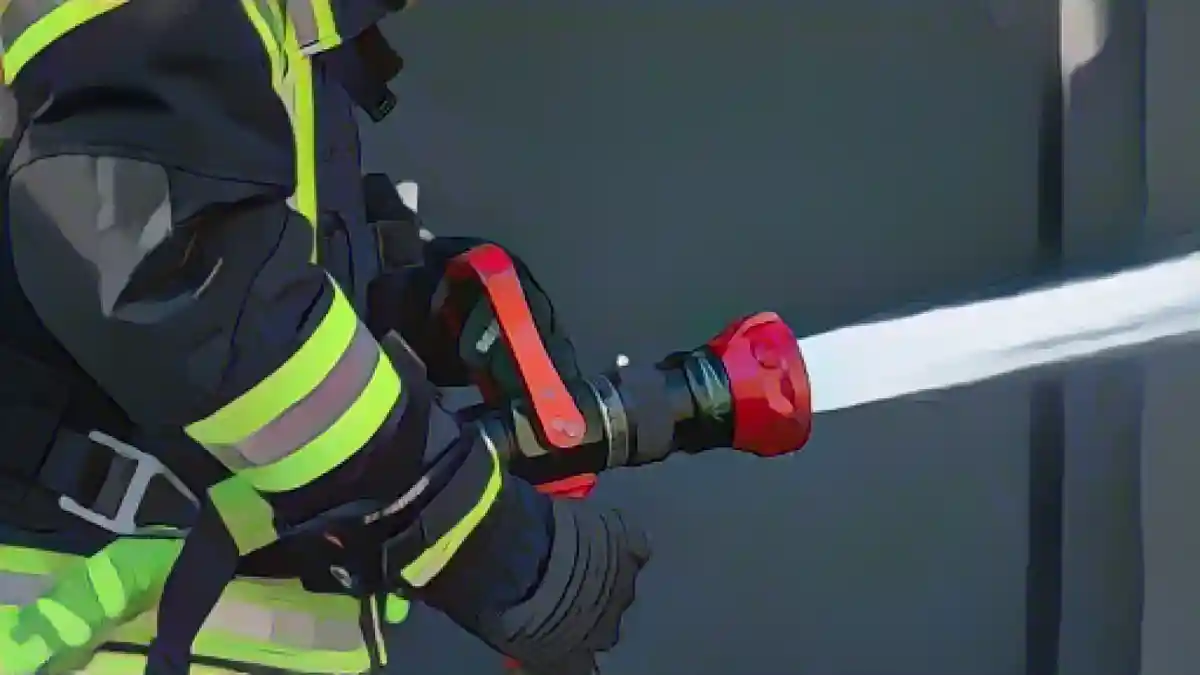Сотрудник пожарной бригады распыляет воду из шланга.:Сотрудник пожарной бригады распыляет воду из шланга. Фото