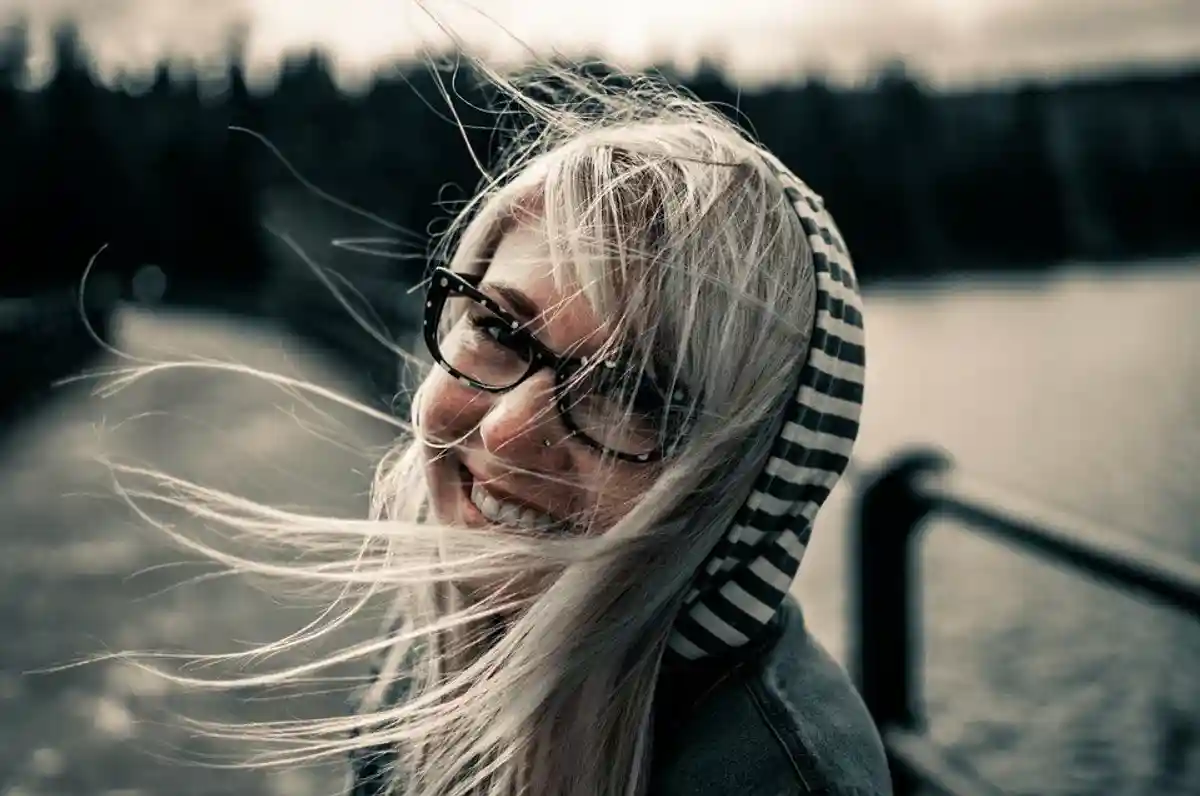 счастливая девушка в капюшоне и очках фото